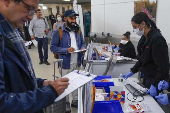 Shubham Chandra, center, returning home to New York from Cancun, Mexico, takes an anonymous COVID tests for study purposes after arriving at Newark Liberty International Airport in Newark, N.J., Wednesday, Jan. 4, 2023. Chandra knows how dangerous the coronavirus can be: He lost his father during the pandemic. So when he cleared customs and saw people offering anonymous COVID-19 testing, he was happy to volunteer. (AP Photo/Seth Wenig)