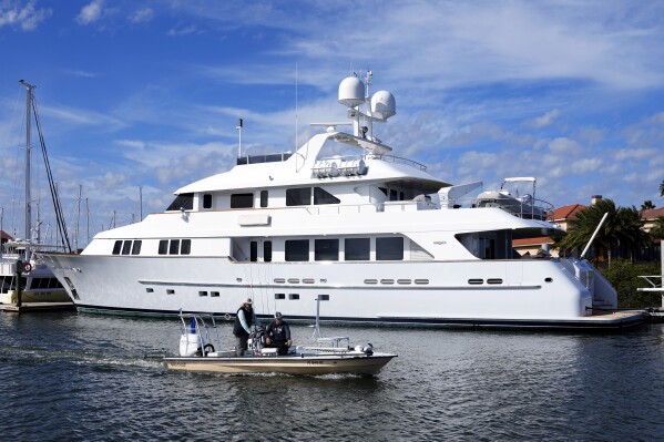 A small craft passes by Igor Makarov's 128-foot yacht, called Areti I docked at Camachee Cove Yacht Harbor marina, Thursday, Nov. 30, 2023, in St. Augustine, Fla. Most of his fortune earned doing business in Russia and the former Soviet Union is frozen, and his plans to develop his energy businesses are currently shelved. His yacht is seized and his two private jets are grounded. Western officials say sanctions against Russia's billionaires are meant to isolate President Vladimir Putin, choke off support for his war and turn powerful business allies against him. But in the 20 months since the invasion, only a handful of sanctioned businessmen have spoken out against him. (AP Photo/John Raoux)