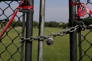 The gates of St. Edwards' Lewis-Chen Family Soccer Field are locked and marked closed due to the coronavirus outbreak, Tuesday, May 5, 2020, in Austin, Texas. In response to the economic impact of COVID-19, St. Edwards says they are cutting cut six sports programs including men's and women's tennis, men's and women's golf and men's soccer. (AP Photo/Eric Gay)