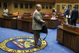 FILE - In this May 26, 2020, file photo, Sen. Frank Pratt, R-Casa Grande, walks with his briefcase off the Senate floor after the Arizona Senate legislative session was adjourned in Phoenix. Longtime Arizona Rep. Frank Pratt has died following a long illness. He was 79. Speaker Rusty Bowers announced Pratt's death on Tuesday, Sept. 21, 2021, and called the Casa Grande Republican "an irreplaceable figure in the Arizona state Legislature." (AP Photo/Ross D. Franklin, File)