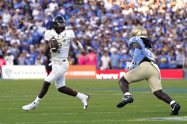 Colorado quarterback Shedeur Sanders, left, tries to pass as UCLA defensive lineman Carl Jones Jr. puts pressure on him during the first half of an NCAA college football game Saturday, Oct. 28, 2023, in Pasadena, Calif. (AP Photo/Mark J. Terrill)