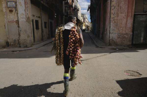 Un vendedor ambulante camina por La Habana Vieja vendiendo cebollas y ajos, en La Habana, Cuba, el miércoles 31 de enero de 2024. (Foto AP/Ramon Espinosa)