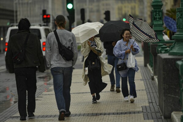 People shelter from the rain under their umbrellas, in San Sebastian, northern Spain, Thursday, Nov. 2, 2023. Authorities have announced heavy rain and wind for next few days along the country. (AP Photo/Alvaro Barrientos)