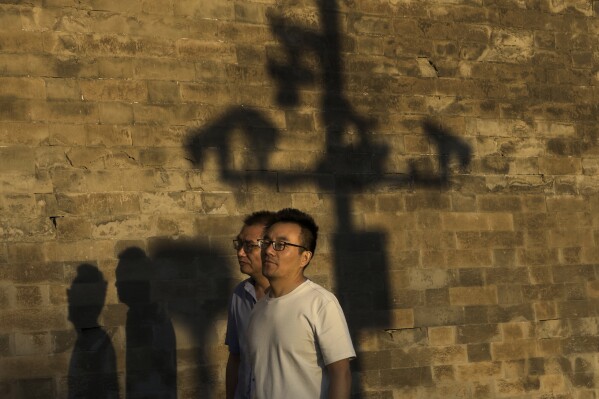 Residents walk by security surveillance cameras casting shadow on the Forbidden City's wall on the eve of the June 4 anniversary, in Beijing, Tuesday, June 3, 2025. (AP Photo/Andy Wong)