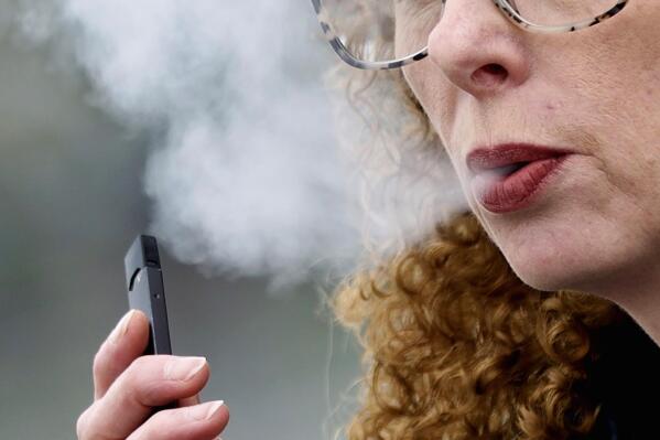 FILE — A woman exhales while vaping from a Juul pen e-cigarette in Vancouver, Wash., April 16, 2019. Juul has asked a federal court, Friday, June 24, 2022, to block a government order to stop selling its electronic cigarettes. Federal health officials on Thursday, June 23,  ordered Juul to pull its electronic cigarettes from the U.S. market, the latest blow to the embattled company widely blamed for sparking a national surge in teen vaping.  (AP Photo/Craig Mitchelldyer, File)