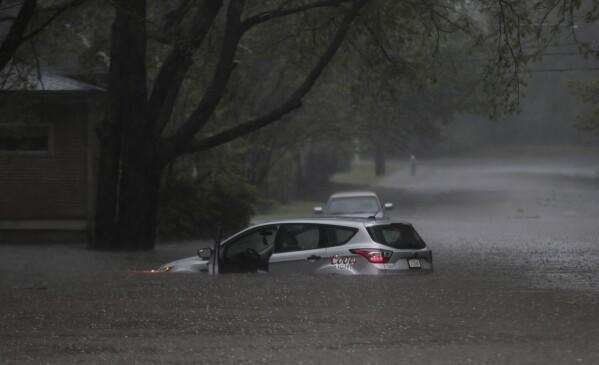 A car is stuck in floodwaters near the corner of Cowden Street and Tanglewood Avenue as heavy rain falls, Saturday, April 5, 2025, in Memphis, Tenn. (Patrick Lantrip/Daily Memphian via AP)