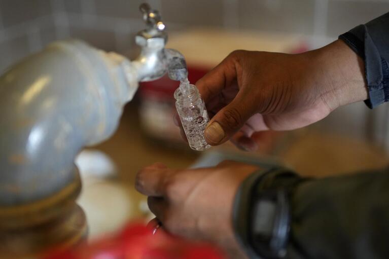 Garnett Querta rinses out a vial after checking the water hauled on his truck on the Hualapai reservation Monday, Aug. 15, 2022, near Peach Springs, Ariz. (AP Photo/John Locher)