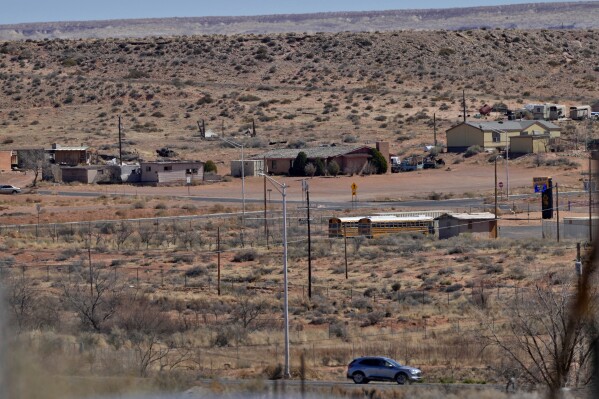 A motorist travels on the Navajo Nation along U.S. 160, Monday, March 4, 2024, in Tuba City, Ariz. with the Hopi reservation shown in the background. This stretch of highway is the de facto border between the Navajo and Hopi Indian reservations and two time zones. Mind-bending time calculations is what people in the largest Native American reservation in the U.S. have to endure every March through November. (AP Photo/Matt York)