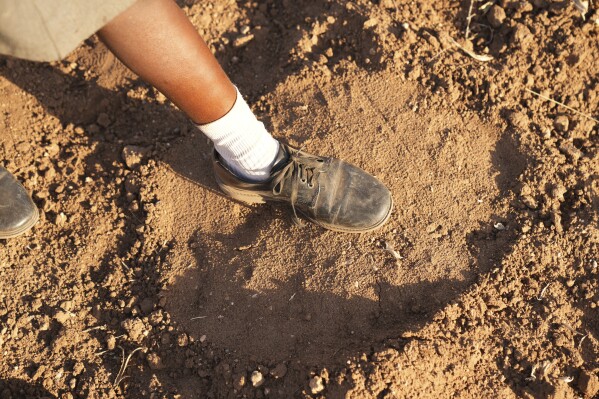 Esther Bote, 14, steps on an elephant footprint on the periphery of Save Valley Conservancy, Zimbabwe on Tuesday, July 9, 2024. The conservancy and the country's parks agency have been running a program for school-age children on how to recognize danger signs and how to coexist with wildlife. (AP Photo/Tsvangirayi Mukwazhi)