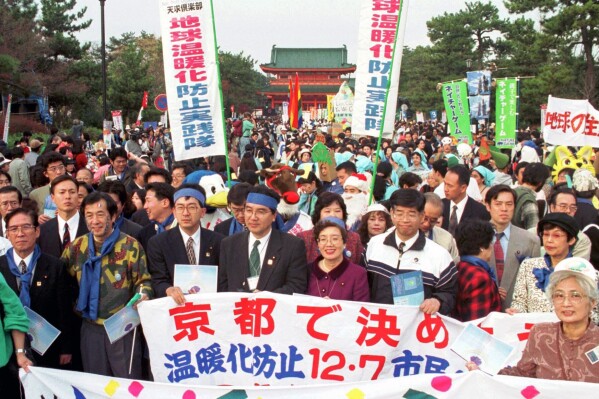 FILE - Environmentalists and citizens hold banners demanding reduction of greenhouse gas emissions in front of Heian Temple in Kyoto, western Japan, on December 7, 1997.  (AP Photo/Katsumi Kasahara, File)