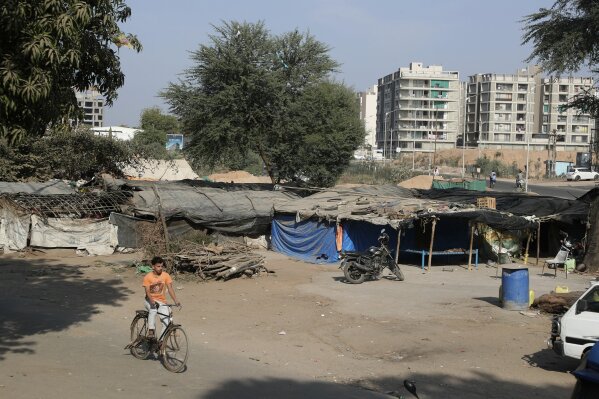 A boy rides a cycle past a slum near Sardar Patel Gujarat Stadium in Ahmedabad, India, Tuesday, Feb. 18, 2020. Authorities on Monday served eviction notices to 45 families living in the slum area ahead of the visit of U.S. President Donald Trump. Trump is visiting the city of Ahmedabad in Gujarat during a two-day trip to India next week to attend an event called “Namaste Trump,” which translates to “Greetings, Trump,” at a cricket stadium along the lines of a “Howdy Modi” rally he hosted for Indian Prime Minister Narendra Modi in Houston last September. (AP Photo/Ajit Solanki)