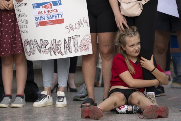 Covenant School student Alex Eissinger-Hansen holds her mother's leg during a demonstration for gun control legislation Tuesday, April 18, 2023, in Nashville, Tenn. Participants created a human chain spreading from Monroe Carell Jr. Children's Hospital at Vanderbilt, where victims of The Covenant School shooting were taken on March 27, to the Tennessee State Capitol. (AP Photo/George Walker IV)