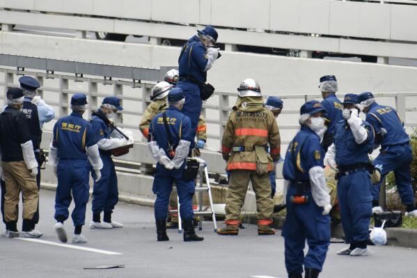 Police and firefighters inspect the scene where a man is reported to set himself on fire, near the Prime Minister's Office in Tokyo, Wednesday, Sept. 21, 2022.  The man was taken to a hospital Wednesday, in an apparent protest against a planned state funeral next week for the assassinated former leader Shinzo Abe, officials and media reports said.(Kyodo News via AP)