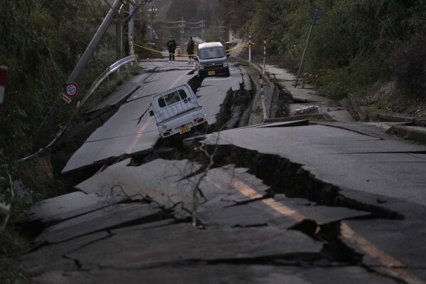 Bystanders look at damages somewhere near Noto town in the Noto peninsula facing the Sea of Japan, northwest of Tokyo, Tuesday, Jan. 2, 2024, following Monday's deadly earthquake. (AP Photo/Hiro Komae)