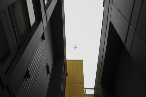 An airplane flies above an open space between two wings of a 'micro apartment' building in Seattle on Monday, March 11, 2024. (AP Photo/Manuel Valdes)