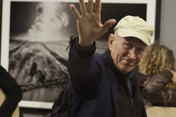 Photographer Sebastiao Salgado waves to photographers during the presentation of his exhibition, 'Kuwait: A Desert on Fire', at the Galleria Meravigli, in Milan, Italy, Oct. 20, 2017. Salgado, known for his long-term projects and images of nature and humanity, died at age 81, the Instituto Terra confirmed on Friday, May 23, 2025. (AP Photo/Luca Bruno, File)
