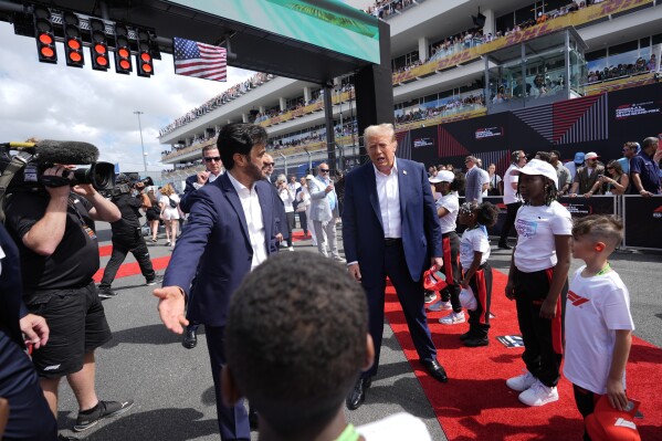 Republican presidential candidate, former President Donald Trump, center, walks along the grid before the Miami Formula One Grand Prix auto race, Sunday, May 5, 2024, in Miami Gardens, Fla. With Trump is FIA President Mohammed Ben Sulayem, left. (AP Photo/Rebecca Blackwell)