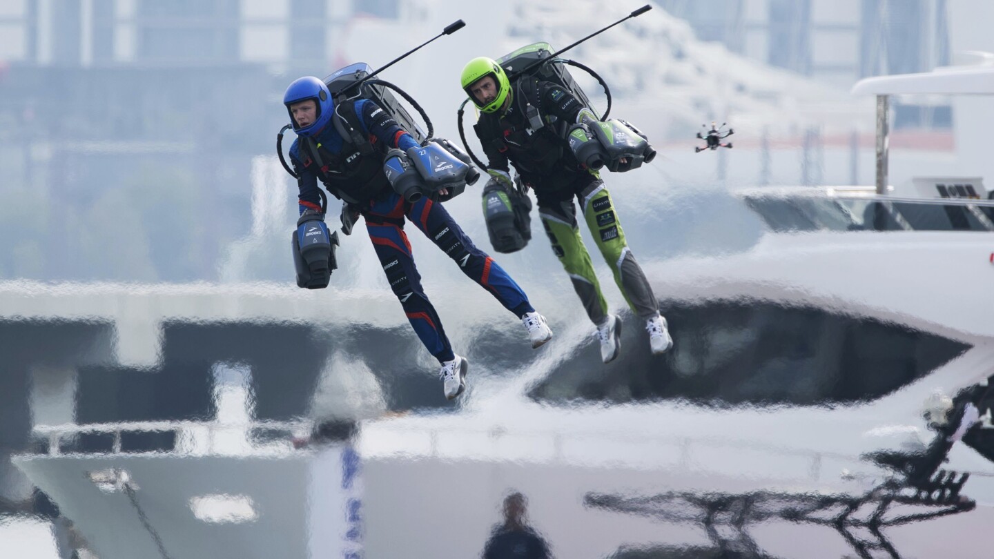 Jet suit pilots race in Dubai, United Arab Emirates, Wednesday, Feb. 28, 2024. Dubai on Wednesday hosted what it called its first-ever jet suit race. Racers zipped along a route with the skyscrapers of Dubai Marina looming behind them, controlling the jet engines on their hands and their backs. (AP Photo/Jon Gambrell)