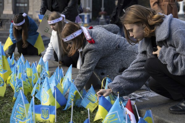 Ukrainian students, who lost relatives due to the Russia-Ukrainian war set flags in their memory on the memorial of fallen Ukrainian soldiers, while attending the reconstruction of a student-led protest campaign "Revolution on Granite" on Independence square in Kyiv, Ukraine, Tuesday, Oct. 17, 2023. (AP Photo/Alex Babenko)