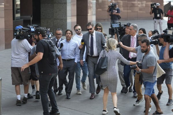 Dr. Mark Chavez, center left, a physician from San Diego, who is charged in connection with actor Matthew Perry's death from an accidental ketamine overdose, arrives with his attorney Matthew Binninger, center right, at the Roybal Federal Courthouse in Los Angeles, Friday, Aug. 30, 2024. (AP Photo/Damian Dovarganes)