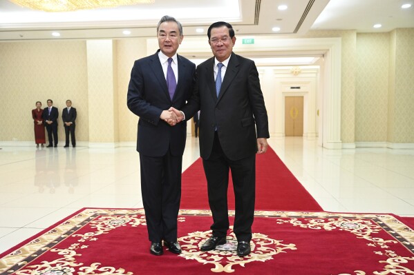 In this photo provided by Kok Ky/Cambodia's Government Cabinet, Cambodian Prime Minister Hun Sen, right, shakes hands with Chinese Foreign Minister Wang Yi, left, during a meeting in Peace Palace in Phnom Penh, Cambodia, Sunday, Aug. 13, 2023. (Kok Ky/Cambodia's Government Cabinet via AP)