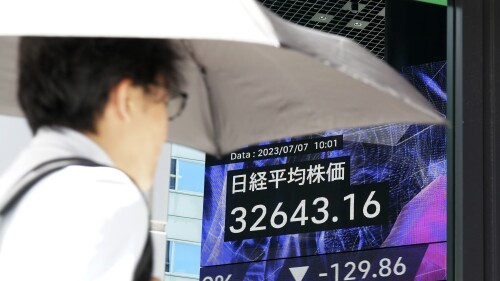 A person walks in front of an electronic stock board showing Japan's Nikkei 225 index at a securities firm Friday, July 7, 2023, in Tokyo. Asian shares slipped Friday after another decline on Wall Street, where hopes for an end to interest rate hikes have been dashed by strong economic data. (AP Photo/Eugene Hoshiko)
