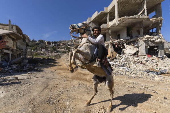 A Lebanese man rides his horse in Kfar Kila, a southern Lebanon village destroyed by an Israeli air and ground offensive, Feb. 18, 2025. (AP Photo/Hassan Ammar)