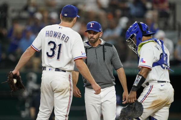Texas Rangers starting pitcher Spencer Howard (31) talks with manager Chris Woodward, center, before turning the ball over as catcher Meibrys Viloria, stands by on the mound in the fifth inning of a baseball game against the Baltimore Orioles, Tuesday, Aug. 2, 2022, in Arlington, Texas. (AP Photo/Tony Gutierrez)
