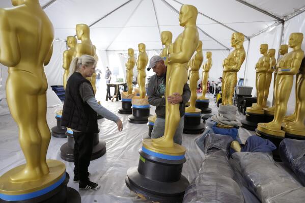 Antje Menikheim, left, lead scenic painter for Sunday's 95th Academy Awards, and scenic artist Michael Thomas prepare Oscar statues for the event, Wednesday, March 8, 2023, near the Dolby Theatre in Los Angeles. (AP Photo/Chris Pizzello)