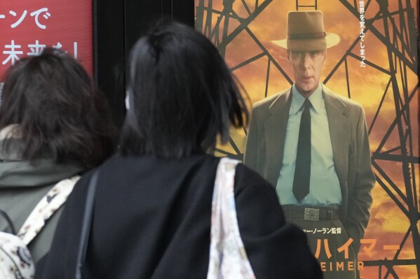 People walk in front of posters of films showing at a movie theater including the seven Academy Award winning movie "Oppenheimer" Friday, March 29, 2024, in Tokyo. (AP Photo/Eugene Hoshiko)