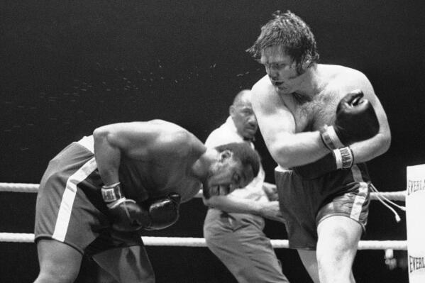 FILE - Heavyweight champion Joe Frazier ducks to miss a right by challenger Ron Stander during their boxing bout May 25, 1972, in Omaha, Neb. In the background is referee Zack Clayton. Stander, whose fight against Frazier in 1972 was the highlight of his 13-year career, has died. He was 77. Toddy Stander said her husband died at home Tuesday, March 8, 2022, from complications of diabetes. (AP Photo, File)