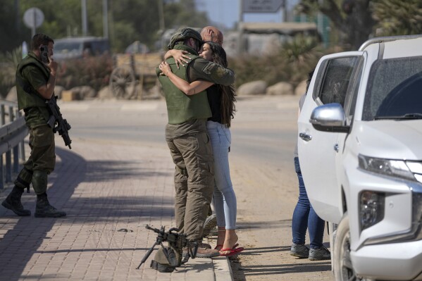 An Israeli soldier hugs his partner near the border with the Gaza Strip, southern Israel, Friday, Oct. 20, 2023. (AP Photo/Ohad Zwigenberg)