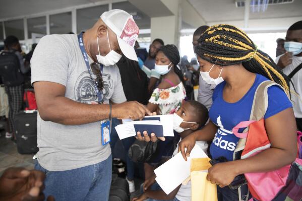 Etienne Ilienses checks her family's papers for a flight to Chile, at the Toussaint Louverture International Airport, in Port-au-Prince, Haiti, Sunday, Jan. 30, 2022. Ilienses said she was sent back to Haiti from Texas on Dec. 14 and talked to the AP before flying to Santiago with her three children on a Jan. 30 charter flight on SKY. “To get to the USA, I braved hell,” she said. Still, she did not dismiss doing it again “because Haiti offers nothing to its children. We are forced to suffer humiliations, affronts everywhere." (AP Photo/Odelyn Joseph)