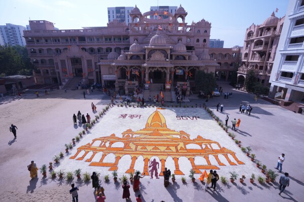 सोमवार, 22 जनवरी, 2024 को भारत के अहमदाबाद में, अयोध्या में हिंदू देवता भगवान राम को समर्पित एक मंदिर के उद्घाटन का जश्न मनाने के लिए बनाए गए विशाल पुष्प डिजाइन को देखते हुए लोग। (एपी फोटो/अजीत सोलंकी)