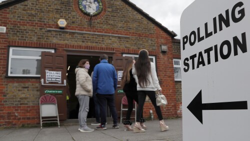 FILE - People queue at the entrance of a polling station in London, on May 6, 2021. Britain’s electoral watchdog said Friday, June 23, 2023 that about 14,000 people were prevented from voting in last month’s local elections because of a new law requiring voters to show photo identification. The Electoral Commission said 0.25% of people who went to polling stations were unable to cast ballots because they didn’t have the right ID, and “significantly more” than that likely did not show up at all. (AP Photo/Frank Augstein, File)