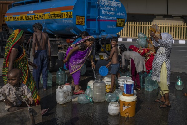 Women and children living in a settlement on the flood plain of Yamuna River, collect drinking water from a municipality tanker in New Delhi, India, Friday, Sept. 29, 2023. (AP Photo/Altaf Qadri)