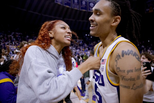 LSU students, including LSU women's basketball forward Angel Reese, left, rush the court after LSU forward Tyrell Ward (15) hit the game-winning shot against Kentucky in an NCAA college basketball game in Baton Rouge, La., Wednesday, Feb. 21, 2024. (AP Photo/Matthew Hinton)