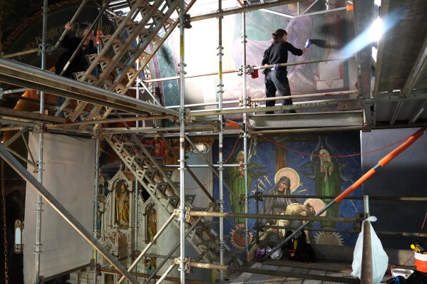 Working on a 32-foot-tall scaffold, art conservator Kate Pirelli works on cleaning a mural by Max Vanka inside St. Nicholas Croatian Catholic Church in Millvale, Pa., Monday, May 19, 2025. (AP Photo/Gene J. Puskar)