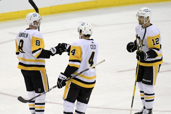 Pittsburgh Penguins defenseman Brian Dumoulin (8) celebrates his goal with defenseman Cody Ceci (4) and center Zach Aston-Reese (12) during the first period of the team's NHL hockey game against the New Jersey Devils on Friday, April 9, 2021, in Newark, N.J. (AP Photo/Bill Kostroun)
