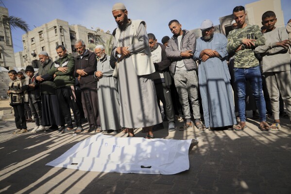 Nashat Seiam, third from right, joins relatives and friends in prayer over the body of his granddaughter Ahlam, who was just days away from her first birthday, during her funeral after she was killed by an overnight Israeli airstrike on her home in Khan Younis, southern Gaza Strip, on Wednesday, April 16, 2025,.(AP Photo/Mariam Dagga)