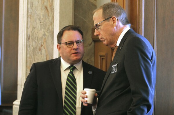 Kansas state Reps. Jesse Borjon, right, R-Topeka, and Mark Schreiber, left, R-Emporia, confer before the House convenes its daily session, Tuesday, March 26, 2024, at the Statehouse in Topeka, Kan. Both lawmakers support a bill to require pornography websites to verify that Kansas visitors are at least 18. (AP Photo/John Hanna)