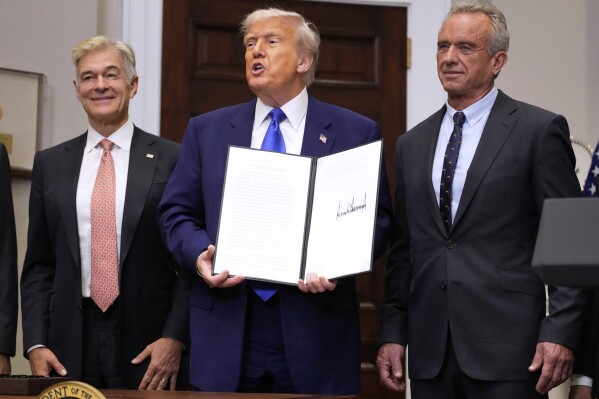 President Donald Trump, with Dr. Mehmet Oz, Administrator of the Centers for Medicare & Medicaid Services, left, and Health and Human Services Secretary Robert F. Kennedy Jr., right, holds an executive order related to drug prices, in the Roosevelt Room of the White House in Washington, Monday, May 12, 2025, in Washington. (AP Photo/Mark Schiefelbein)