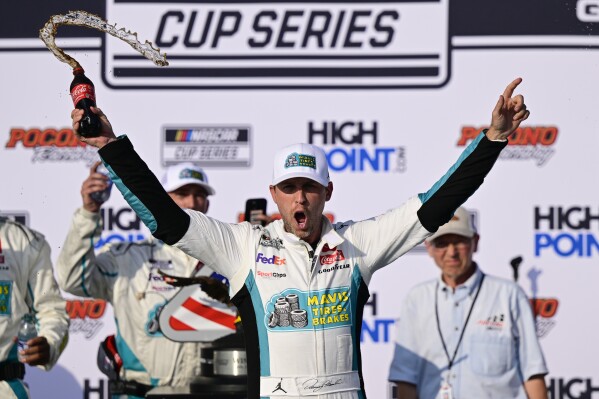 Denny Hamlin celebrates in Victory Lane after winning a NASCAR Cup Series auto race at Pocono Raceway, Sunday, July 23, 2023, in Long Pond, Pa. (AP Photo/Derik Hamilton)