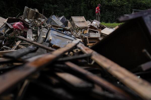 FILE - A man stands near a pile of debris as residents start to clean up and rebuild in Fleming-Neon, Ky., Aug. 5, 2022, after massive flooding the previous week. Gov. Andy Beshear pointed to signs of progress Thursday, Aug. 18, as federal emergency personnel respond to requests for assistance in flood-ravaged eastern Kentucky, but stressed it is “still not enough” as people work to recover from the disaster that swept away homes and inundated communities. (AP Photo/Brynn Anderson, File)