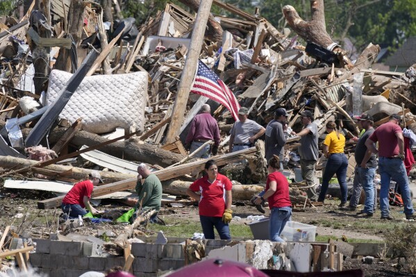 Local residents clean up debris from a tornado damaged home, Wednesday, May 22, 2024, in Greenfield, Iowa. (AP Photo/Charlie Neibergall)