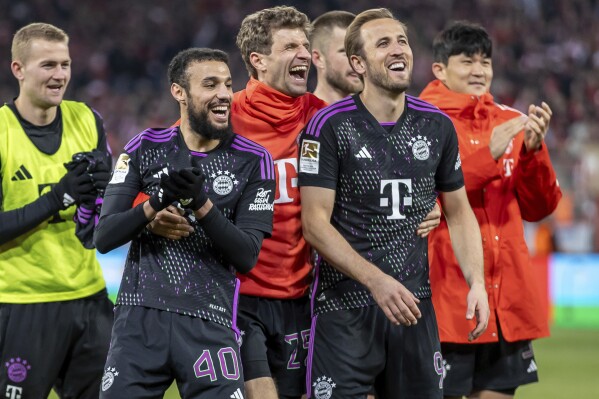 Noussair Mazraoui, from left, Thomas Müller and Harry Kane of Bayern Munich celebrate in front of the crowd after the German Bundesliga soccer match between FC Union Berlin and Bayern Munich at the An der Alten Forsterei stadium in Berlin, Germany, Saturday, April 20, 2024. (Andreas Gora/dpa via AP)