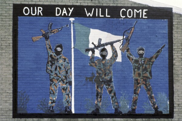 FILE - A wall painting supporting the Irish Republican Army, seen in the Catholic area of Belfast, Northern Ireland on Nov. 1985. A seven-year investigation into the activities of a former Irish Republican Army double agent concluded Friday that the spy was probably responsible for more deaths than lives saved during Northern Ireland's three-decade conflict. The probe, known as Operation Kenova, investigated the actions of “Stakeknife,” a senior IRA member who was passing information to British intelligence during “the Troubles.” (AP Photo/Peter Kemp, File)