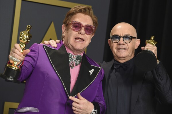 FILE - Elton John, left, and Bernie Taupin, winners of the award for best original song for "(I'm Gonna) Love Me Again" from "Rocketman", pose in the press room at the Oscars on Sunday, Feb. 9, 2020, in Los Angeles. Taupin's memoir, "Scattershot: Life, Music, Elton, and Me" releases this week. (Photo by Jordan Strauss/Invision/AP, File)