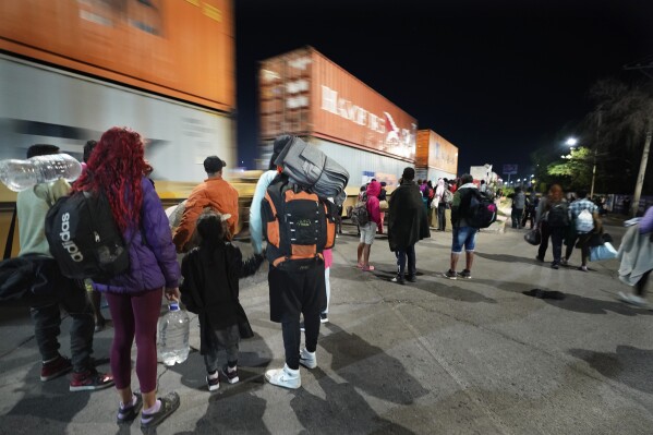 Migrantes miran un tren de mercancías mientras esperan a un tren rumbo al norte que se detenga el tiempo suficiente para subir a él, en Irapuato, México, el sábado 23 de septiembre de 2023. (AP Foto/Marco Ugarte)