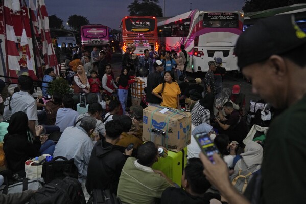 People wait for their buses as they leave for their hometowns ahead of the Eid al-Fitr holiday at Kalideres Bus Terminal in Jakarta, Indonesia, Saturday, April 6, 2024. Millions of Indonesians are packing bus and train stations, airports and highways as they head to hometowns to celebrate Thursday's Eid al-Fitr festival with family. (AP Photo/Dita Alangkara)